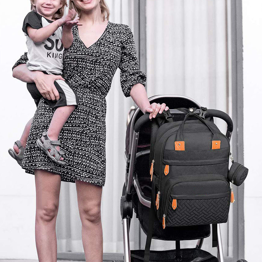 Mum carrying child while wearing stylish black nappy bag backpack for everyday use